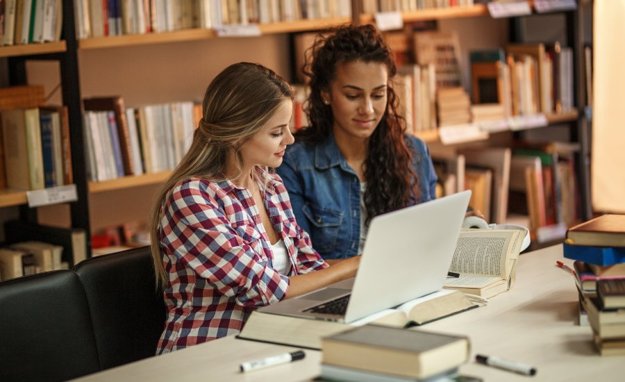 2 women studying with a laptop and books