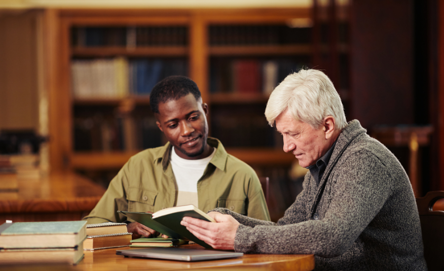 2 men reading a book in a library