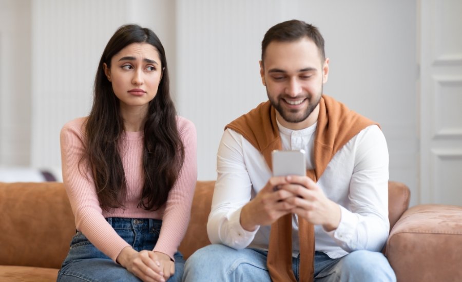 one woman looking confused and one men holding a phone and smiling at it