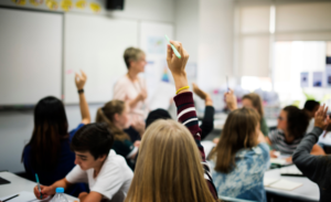 Children in a classroom raising their hands