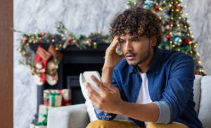 Man looking at his phone stressed with a holiday background.