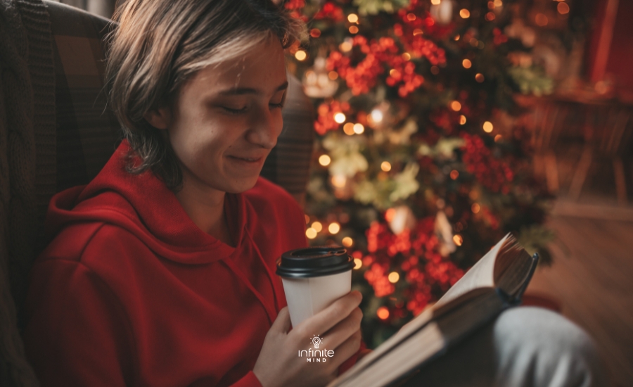 Portrait of candid, authentic smiling boy teenager reading a book at home on Xmas