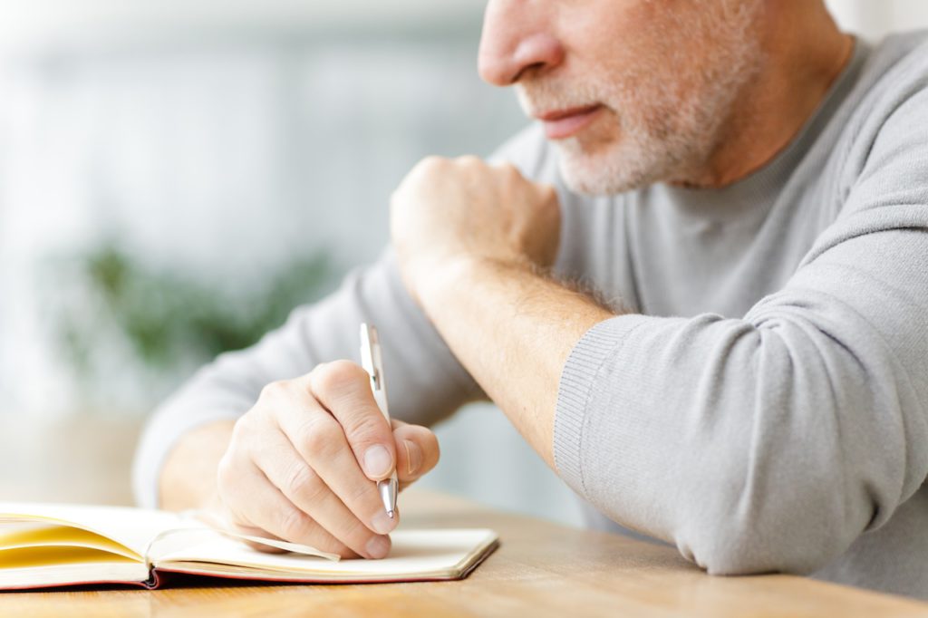 man writing in journal to train his brain
