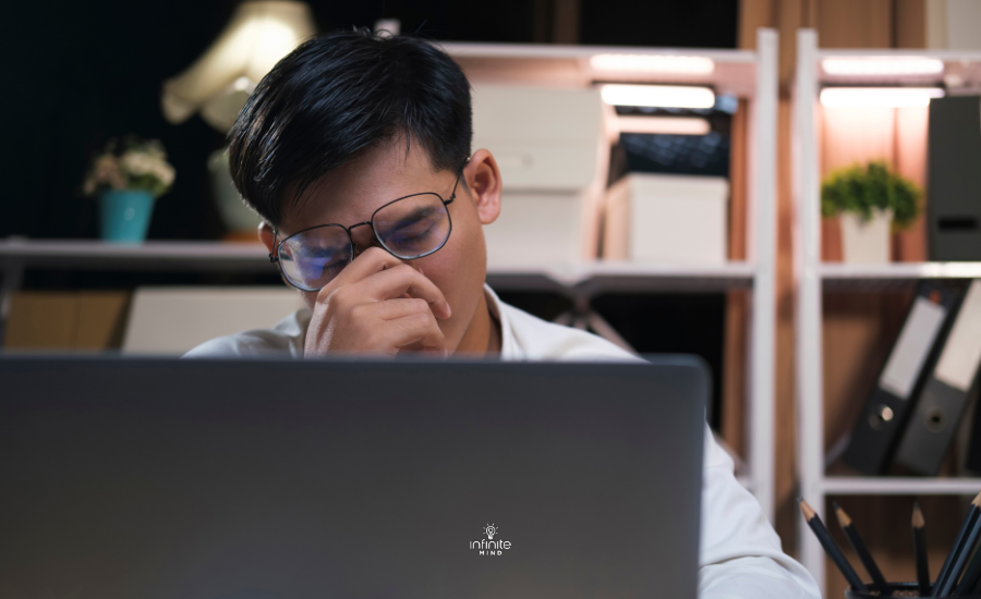 Exhausted young man with laptop in office.