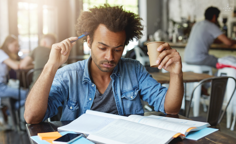 Concentrated thoughtful black student with studying drinking coffee
