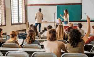 A student at the blackboard giving answers before the eyes of his teacher and classmates