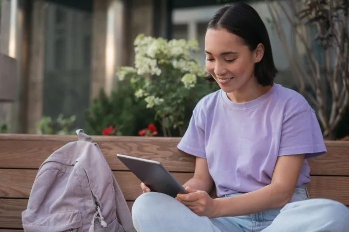 A view of a young woman studying on a tablet outdoors — Unlock your student's potential with 5 proven brain training exercises.