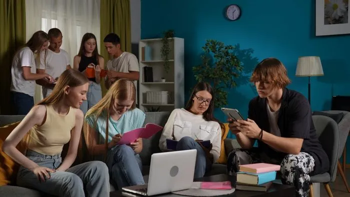 A view of students collaborating and practicing reading skills with digital devices and notebooks in a cozy study space.
