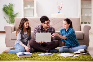 A view of three people studying together with a laptop and books in a cozy living room, enhancing focus and learning.