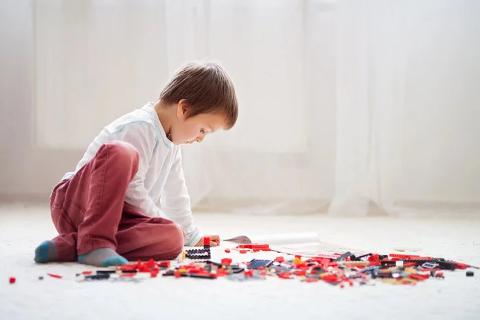 A view of a child sitting on the floor focused on building with colorful bricks illustarting Intrapersonal Intelligence