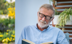 Senior Elderly Man Wearing Glasses Reading Book In Garden