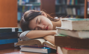 Tired Woman Sleeping on Books in Library